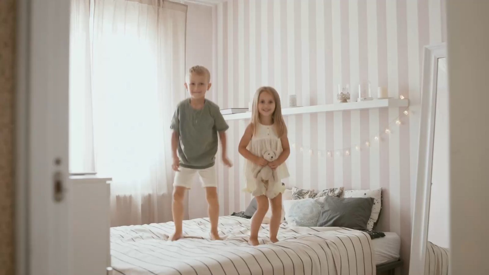 Två barn som hoppar i sängen hemma